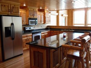 Whispering pines log home interior kitchen with light pine cabinets & black counter tops