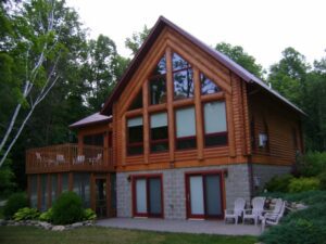 Whispering Pines projects log home exterior with large windows and upper deck