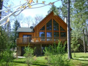 Whispering pines projects log home exterior with large windows and upper deck