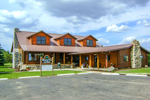 Exterior of Whispering Pines Log Homes office and example of Hickory style log home